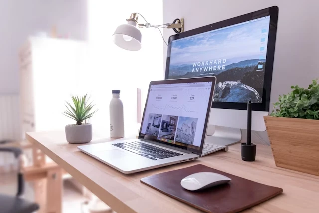Modern desk setup with a laptop and monitor displaying a website